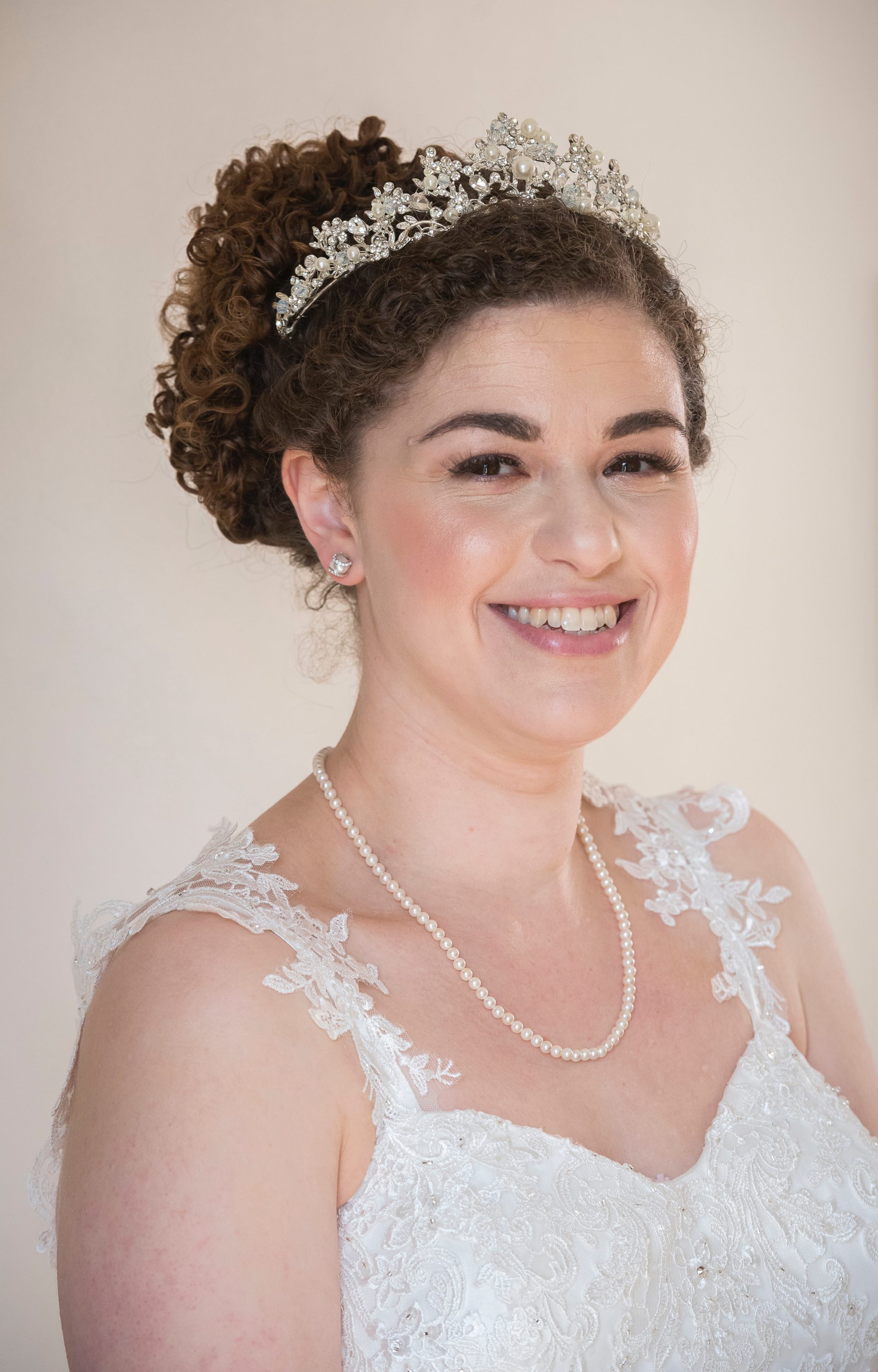 naturally curly updo with a pearl and jewel crown