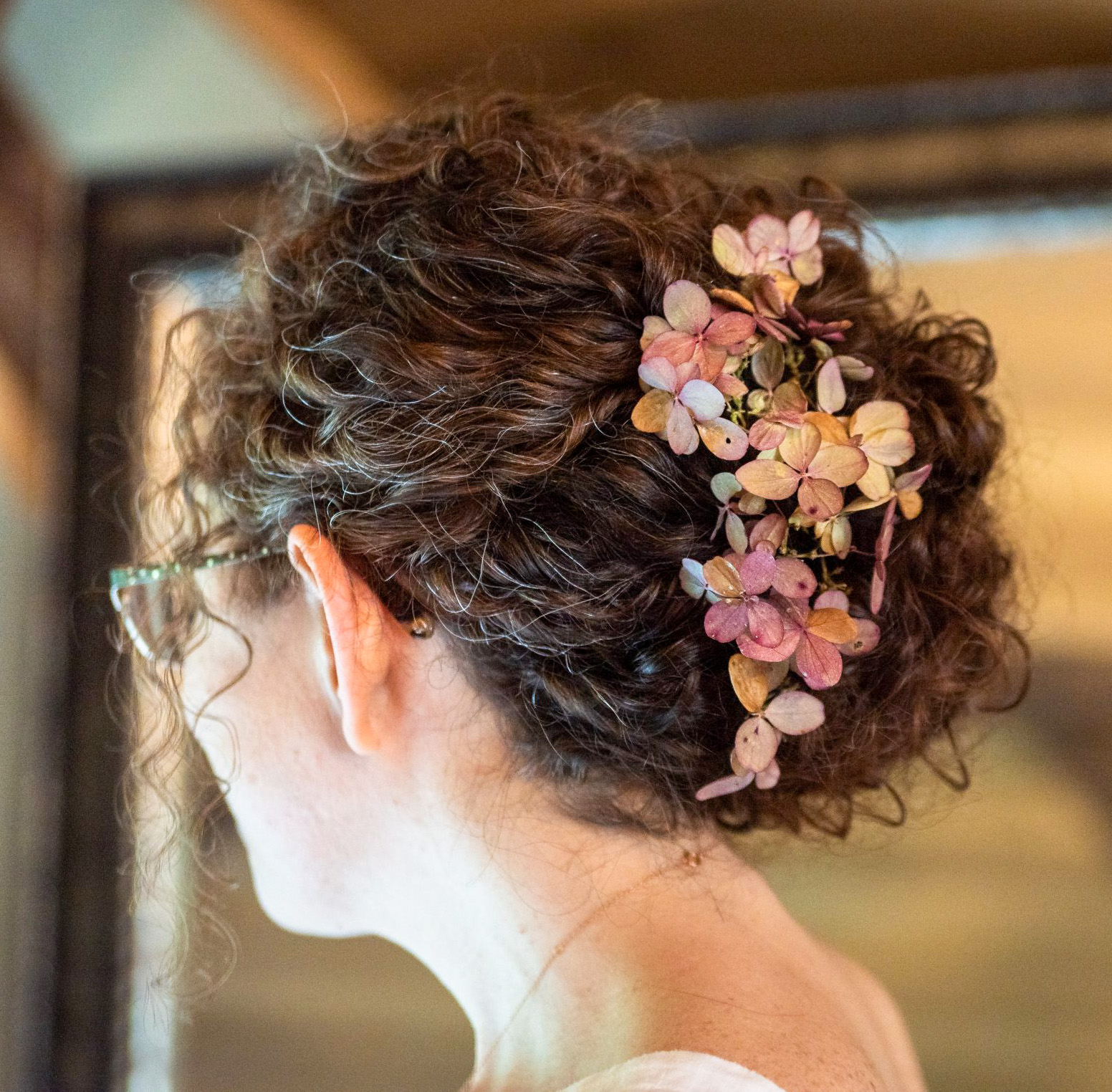 curly bridal updo with floral hair accessory